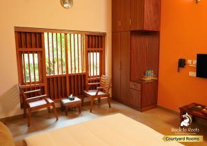 sala de estar con 2 sillas y paredes de color naranja en Back to Roots Ayurveda Retreat, en Kizhake Chālakudi