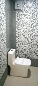 a bathroom with a toilet and a black and white wallpaper at Corbett Bhavesh home Stay in Jhirna