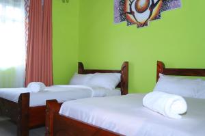 3 camas en una habitación con paredes verdes en Esniko Villa, en Narok