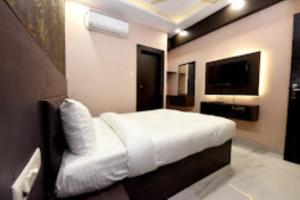 sypialnia z białym łóżkiem i telewizorem z płaskim ekranem w obiekcie Hotel VK INN Prayagraj w mieście Prayagraj