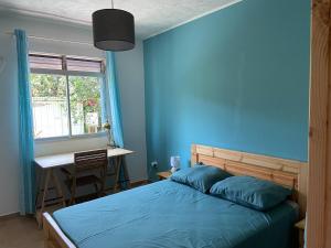 Schlafzimmer mit blauen Wänden, einem Bett und einem Schreibtisch in der Unterkunft Villa T4 Garden With See-view in Petit-Bourg