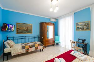1 dormitorio con 2 camas y pared azul en Casa delle Zammare Fronte mare centro storico, en Riposto