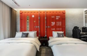 two beds in a room with a red door at Gimpo JK Hotel in Gimpo