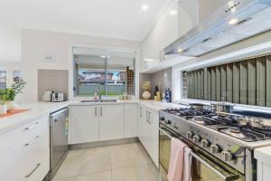 a kitchen with white cabinets and a stove top oven at Vivid House in Marsden Park in Marsden Park