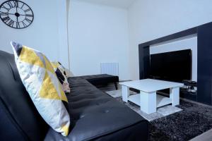 sala de estar con sofá negro y TV en Élégant appartement bord de Seine, en Montereau-Fault-Yonne
