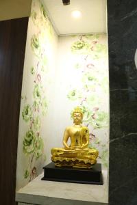 uma estátua de Buda de ouro em frente a uma parede em Hotel J B L em kolkata