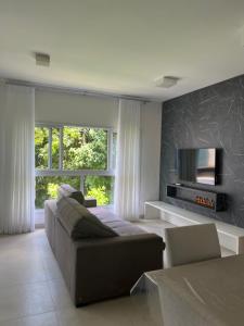 sala de estar con sofá y TV en Apartamento Praia Grande, en Ubatuba