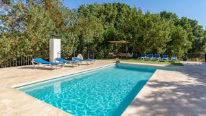a swimming pool with blue chairs and a table and trees at Molino Higueral Villanueva del Trabuco by Ruralidays in Villanueva del Trabuco