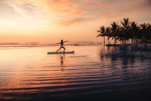 een persoon op een surfplank in het water op het strand bij Sheraton Grand Danang Resort & Convention Center in Da Nang