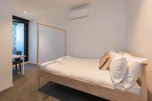ein kleines Schlafzimmer mit einem Bett mit weißer Bettwäsche und Kissen in der Unterkunft 2-bed Apt w Pool Gym & Parking! Near Albert Park in Melbourne