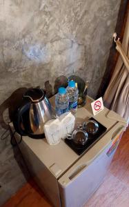 a table with a tea kettle and water bottles on it at เรินนายหัว by KOYAD 
