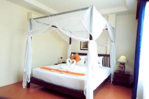 a bedroom with a white bed with a canopy at Harmony Patong Hotel in Patong Beach