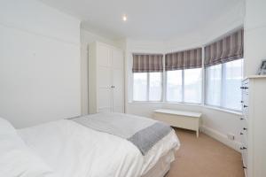 a white bedroom with a bed and two windows at Beautiful 2 Bedroom Flat on Street Lane in Moortown