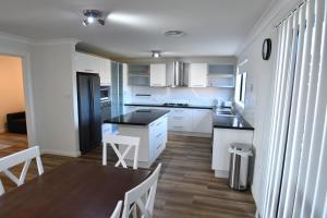 a kitchen with white cabinets and a table and chairs at Ascot Gardens Serviced Apartments in Dubbo