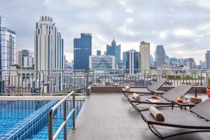 einen Balkon mit Stühlen und Stadtblick in der Unterkunft Adelphi Suites Bangkok - SHA Extra Plus in Bangkok