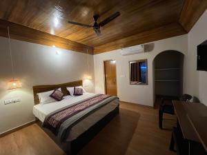 a bedroom with a bed with a ceiling fan at Wild Planet Corbett Hotel and Resort in Rāmnagar