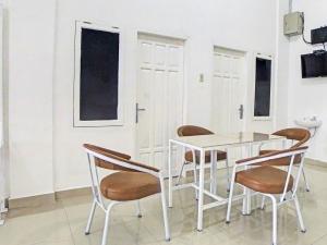 ein weißes Esszimmer mit einem weißen Tisch und Stühlen in der Unterkunft OYO 92950 Orien Guesthouse in Pematangsiantar