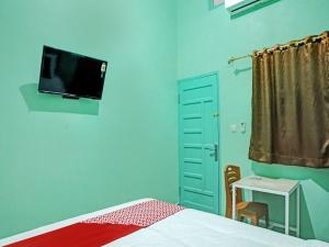 ein Schlafzimmer mit einem Bett und einem TV an der Wand in der Unterkunft OYO 92950 Orien Guesthouse in Pematangsiantar