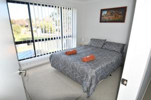 a bedroom with a bed with two orange pillows on it at Ascot Gardens Serviced Apartments in Dubbo