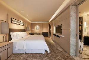 um quarto com uma grande cama branca e uma televisão de ecrã plano em The Westin Ningbo em Ningbo