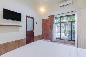- une chambre avec un lit et une télévision murale dans l'établissement Penginapan Asri, à Mataram