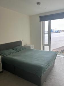 a bedroom with a bed and a large window at Luxury Riverside Apt with easy access to Central London, O2, Excel centre and Parking in Woolwich