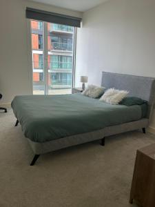 a bed in a room with a large window at Luxury Riverside Apt with easy access to Central London, O2, Excel centre and Parking in Woolwich