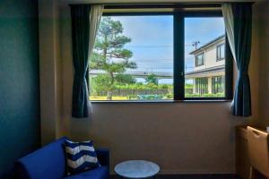 sala de estar con sofá azul y ventana grande en 奥松島LANEホテル en Tōna