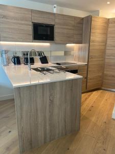 cocina con encimera blanca y armarios de madera en Luxury Riverside Apt with easy access to Central London, O2, Excel centre and Parking en Woolwich