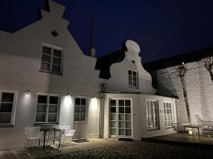 biały budynek z krzesłami i stołem w nocy w obiekcie Baltische Rose w mieście Warnemünde