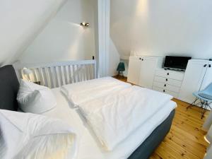 sypialnia z łóżkiem z białą pościelą i biurkiem w obiekcie Baltische Rose w mieście Warnemünde