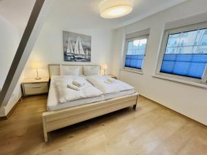 a bedroom with a bed with white sheets and two windows at Ferienwohnung beach, ca 150 m zum Strand in Warnemünde