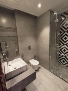 a bathroom with a toilet and a sink and a shower at Taj Studios - Luxury Suit at Blue Sapphire Mall #US Cinema #PizzaHut #HIRA Sweets #Food Court etc by GHUMLOO-COM in Ghaziabad
