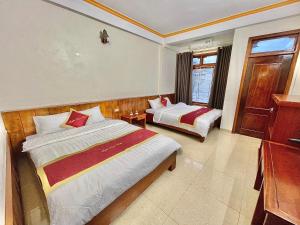 a hotel room with two beds and a dresser at Happy Hotel & Spa in Sapa