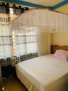 sypialnia z białym łóżkiem z baldachimem w obiekcie Julia Top Holiday Home w mieście Diani Beach