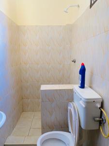 łazienka z toaletą z niebieską butelką na górze w obiekcie Julia Top Holiday Home w mieście Diani Beach