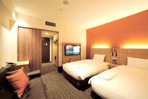 札幌市にあるホテルネッツ札幌のベッド2台、薄型テレビが備わるホテルルームです。