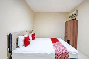 a bedroom with a bed with red and white pillows at OYO Life 93111 Garden Homestay 2 Merlion in Lontar