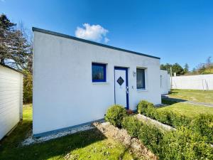 uma casa branca com uma porta azul num quintal em Ferienhaus Lotse em Warnemünde