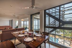 a dining room with a table and a large window at SaffronStays Mountain Rizz in Panchgani