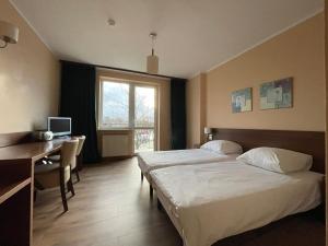 Motel Pieprzyk في كولوبرزيغ: غرفة فندقية بسريرين ومكتب ونافذة