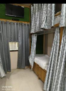 a bunk bed with curtains and a television in a room at Shree Madhvam AC Dormitory in Varanasi