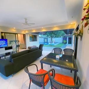 ein Wohnzimmer mit einem Sofa, einem Tisch und Stühlen in der Unterkunft Sunny2 Villa Pattaya in Ban Huai Yai