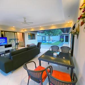 Una sala de estar con un sofá, una mesa y sillas. en Sunny2 Villa Pattaya, en Ban Huai Yai