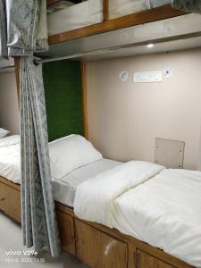 two bunk beds with white sheets and a green wall at Shree Madhvam AC Dormitory in Varanasi