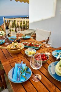a wooden table with plates of food and wine glasses at Kleine Villa mit Meerblick, Samos, Griechenland in Samos