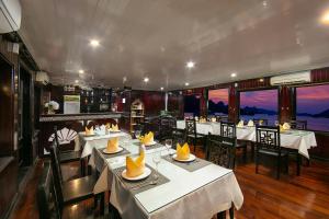 um restaurante com mesas e cadeiras num quarto em Ha Long Fantasea Legend Cruise em Ha Long