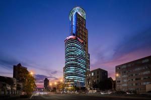 a tall building is lit up at night at Novotel Atlantis Shanghai - Enjoy our great-valued breakfast in our rooftop revolving restaurant with a stunning river view & utilize our FREE self-serviced laundry in Shanghai