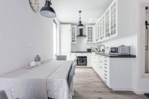 a kitchen with white cabinets and a table in a room at Close-Golden Apartments Gdańsk&K2A in Gdańsk