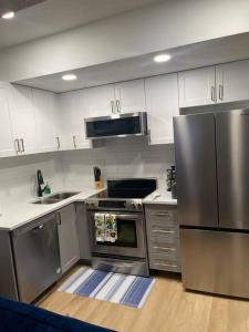 a kitchen with stainless steel appliances and white cabinets at Stylish 2 Bedroom suite in SW Edmonton close to Windermere and Edmonton International Airport in Edmonton